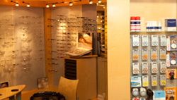 Optikergeschäft mit Brillengestellen an der Wand und Kontaktlinsen-Zubehör im Regal.